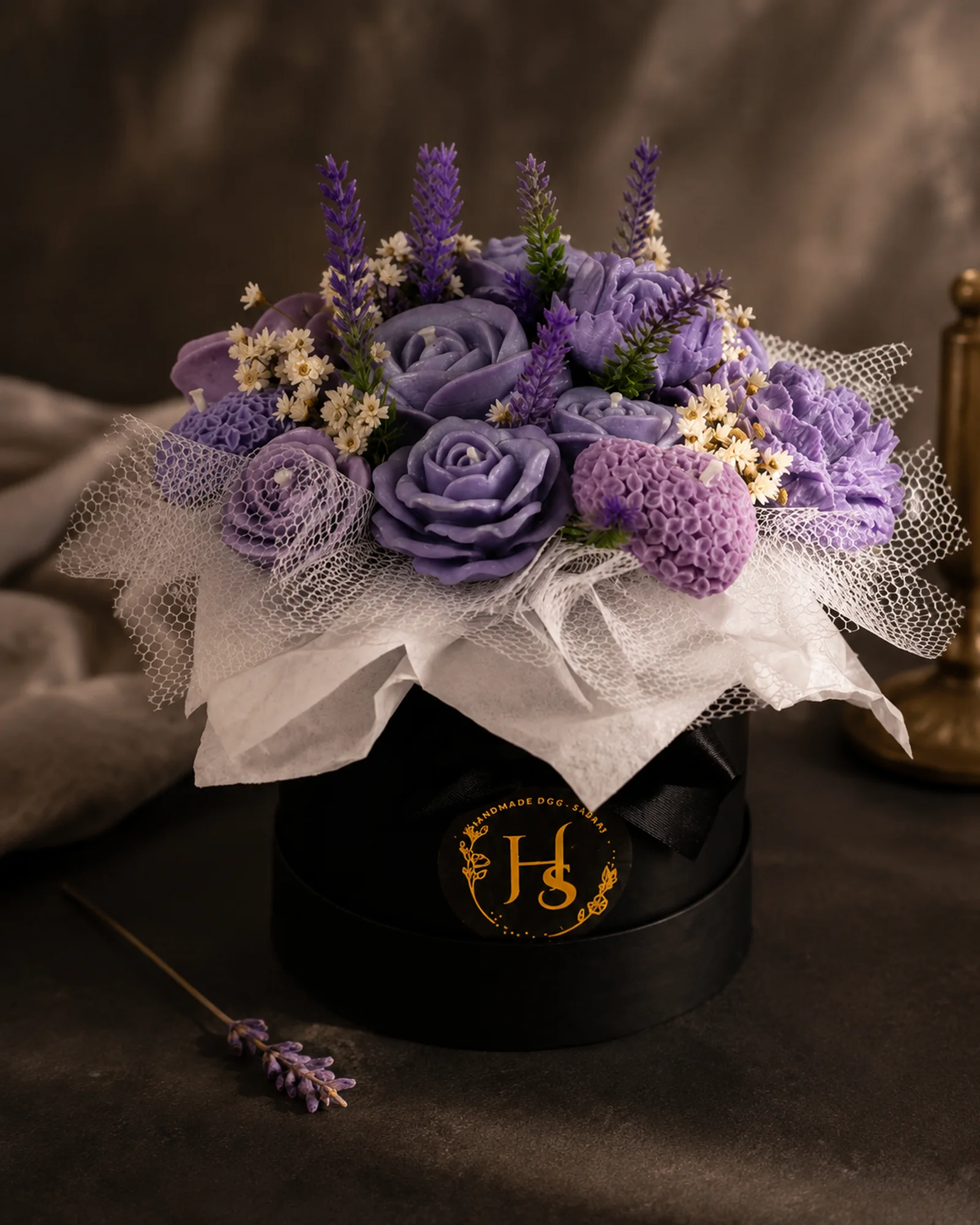 Buquê de velas em lavanda sobre caixa preta com monograma dourado